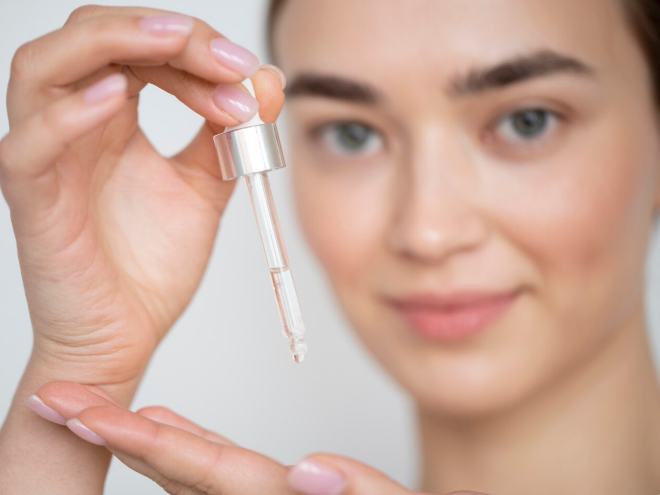 Woman applying retinol serum using a dropper as part of an anti-aging skincare routine.