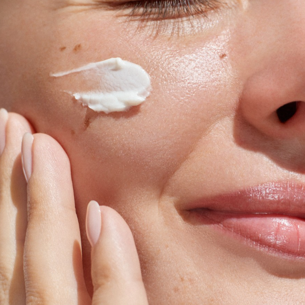 Close-up of a woman applying moisturizing cream to the face as part of an anti-aging skincare routine.