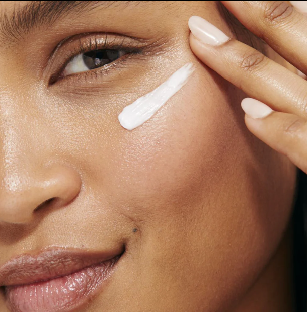 Close-up of a woman applying eye cream to the under-eye area as part of an anti-aging skincare routine.
