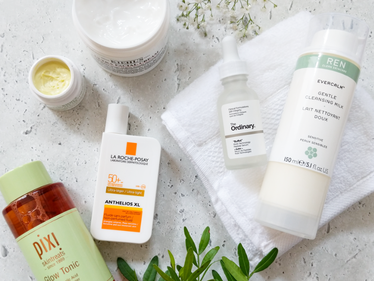 Flat lay of dermatologist-recommended skincare products including cleanser, serum, moisturizer, and sunscreen for an anti-aging routine.